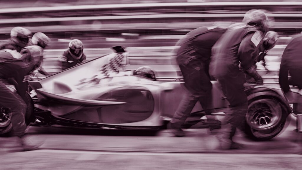 A Formula 1 pit crew working on a race car, in black and white with a berry tint